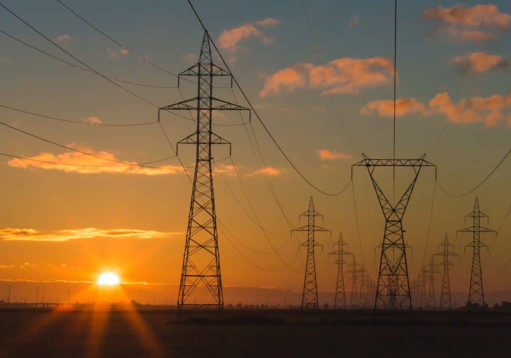 Stora kraftledningar för distribution av el i soluppgång.